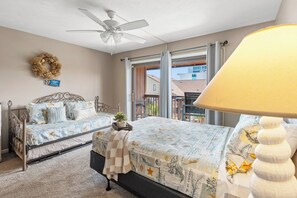 A bedroom with two beds, a ceiling fan, a view of the outside, and a balcony.