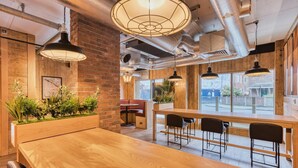 Ein modernes Interieur mit freiliegenden Backsteinwänden, Holztischen und Pendelleuchten.