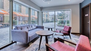 Ein modernes Interieur mit einer Couch, Sesseln, einem kleinen Tisch und großen Fenstern mit Blick nach draußen.
