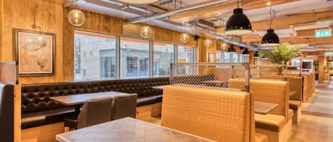 Un restaurant aux murs en bois, avec des banquettes en cuir et des lampes suspendues.
