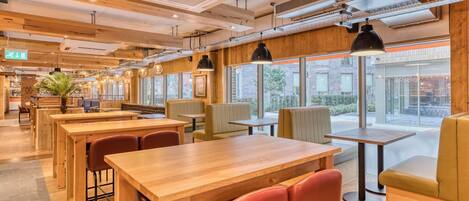 A restaurant interior with wooden tables, booths, and hanging pendant lights.