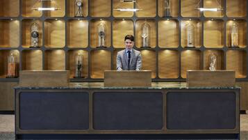Un comptoir d’accueil d’hôtel au design moderne, agrémenté d’une série de vitrines éclairées en arrière-plan.