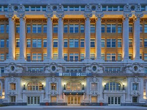 Un edificio imponente con grandes columnas, ventanas arqueadas y un cartel que dice 'Hyatt Place'.