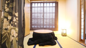 A tatami mat room with a low table, a shoji screen, and a traditional Japanese lantern. - Trad Guest House Kyoto (Kyoto)