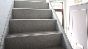 A staircase with carpeted steps leading to a door with a sign above it. - Furere Shichijo (Kyoto)