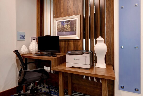 Escritorio de madera con una computadora, impresora y objetos decorativos.