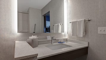 A modern bathroom with a large mirror, a sink, and a towel rack.