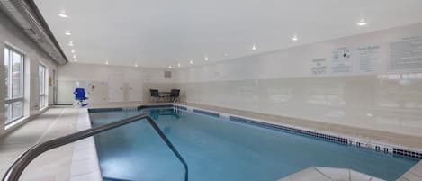 An indoor swimming pool with clear pool rules and safety warnings on the walls.