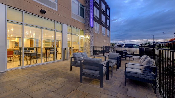 Un espace extérieur aménagé en terrasse, avec des sièges, et un restaurant entièrement vitré.
