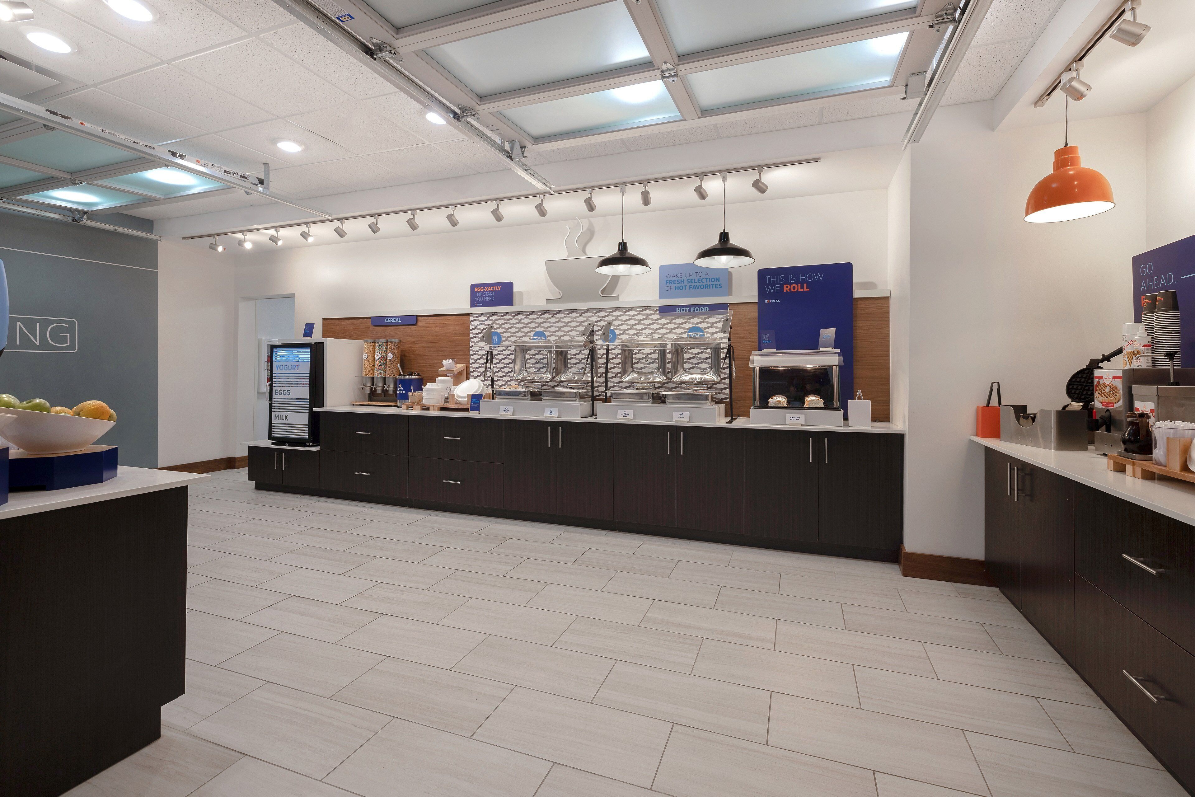 A modern kitchen with dark cabinets, a central island, and a digital menu display.