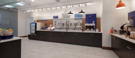 A modern kitchen with dark cabinets, a central island, and a digital menu display.