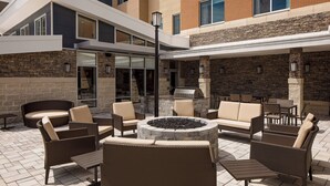 Eine Terrasse im Freien mit Korbmöbeln, einem Feuerkorb und einer Steinwand.