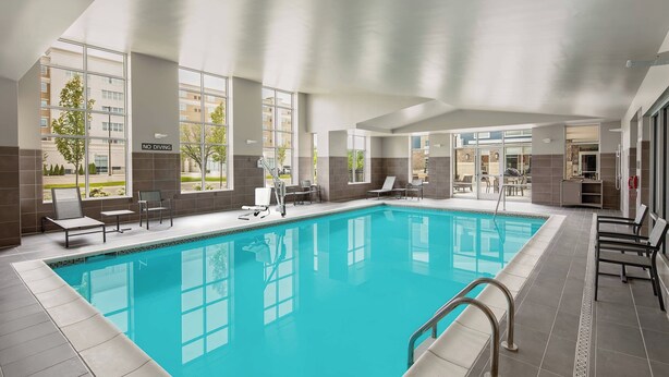 Ein großer, überdachter Swimmingpool mit klarem, blauem Wasser, umgeben von Liegestühlen und einem Schild mit der Aufschrift 'NO DIVING'.