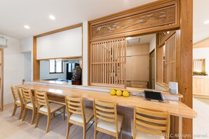 A modern kitchen with a wooden island, bar stools, and a laptop. - Oyado Midokoi (Akune)