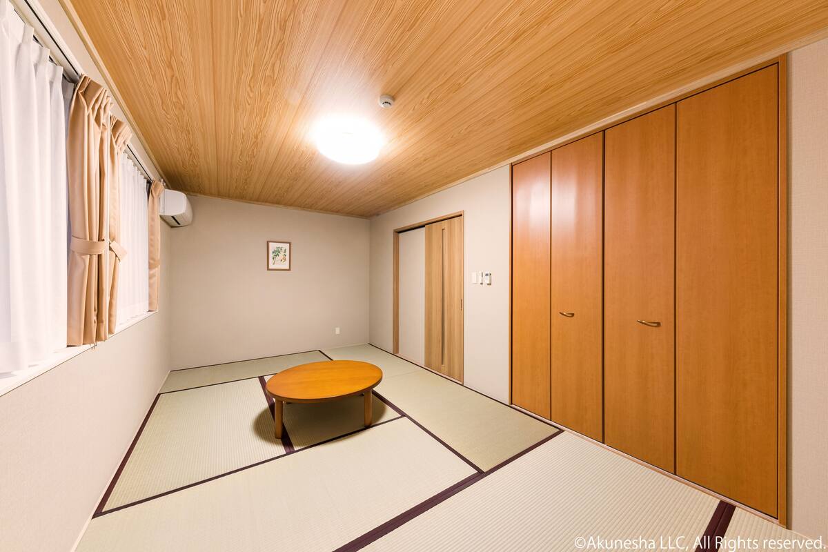 Una habitación con suelo de tatami, techo de madera y un armario.
