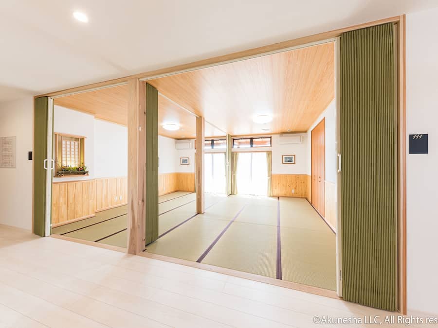 Una habitación japonesa tradicional con suelo de tatami, puertas correderas y techo de madera.