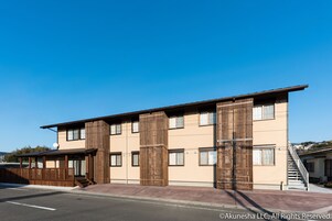 A modern building with a flat roof, multiple windows, and a wooden fence.