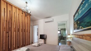 A hotel room with a bed, a TV, a painting, and a wooden wardrobe. - Vacation home SinAgo by Interhome (Lascari)