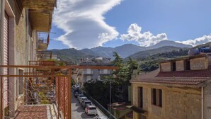 A residential street with parked cars, a metal fence, and a mountain in the background. - Vacation home SinAgo by Interhome (Lascari)