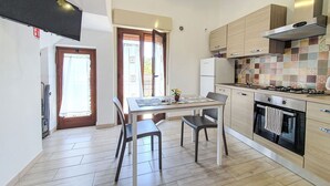 A modern kitchen with a dining area, a refrigerator, a stove, and a tiled backsplash. - Vacation home SinAgo by Interhome (Lascari)