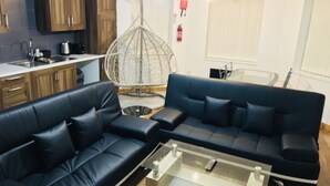 A modern living room with a black leather sofa, a glass coffee table, and a hanging chair. - Green Apartments (Manchester)