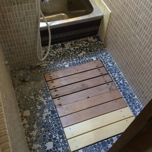 Un baño con piso de mosaicos, un banco de madera y un lavamanos.