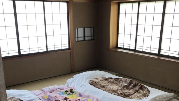 A traditional Japanese room with tatami flooring, two tatami mats, a small window with a grid pattern, and a hanging light fixture. - Kanazawa-Hachitabi Hashiba (Kanazawa)