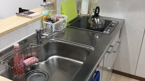 A modern kitchen with stainless steel appliances, a sink with a dish rack, and a green cutting board.