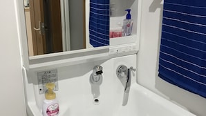 A white bathroom sink with a mirror above it, a blue towel hanging on the wall, and a bottle of hand soap on the sink.