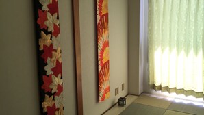 Une pièce de style japonais traditionnel, avec un sol recouvert de tatamis, un paravent shoji et deux rouleaux suspendus au mur.