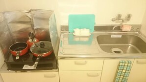 Une cuisine équipée d’une cuisinière, de casseroles, d’un évier et d’une planche à découper bleue.
