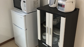 A compact kitchenette with a microwave, a small refrigerator, and a cabinet with a kettle and a rice cooker. - Kanazawa-Hachitabi Konjiki (Kanazawa)