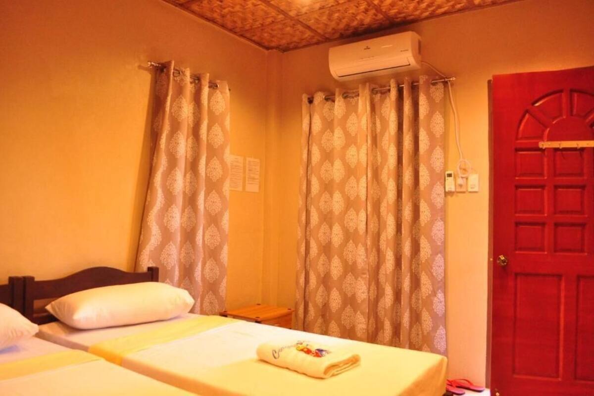 Una habitación de hotel con una cama, una puerta roja y cortinas estampadas.