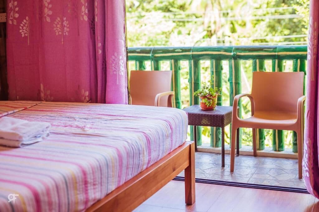 Un dormitorio con una cama, una mesita con una planta y dos sillas.