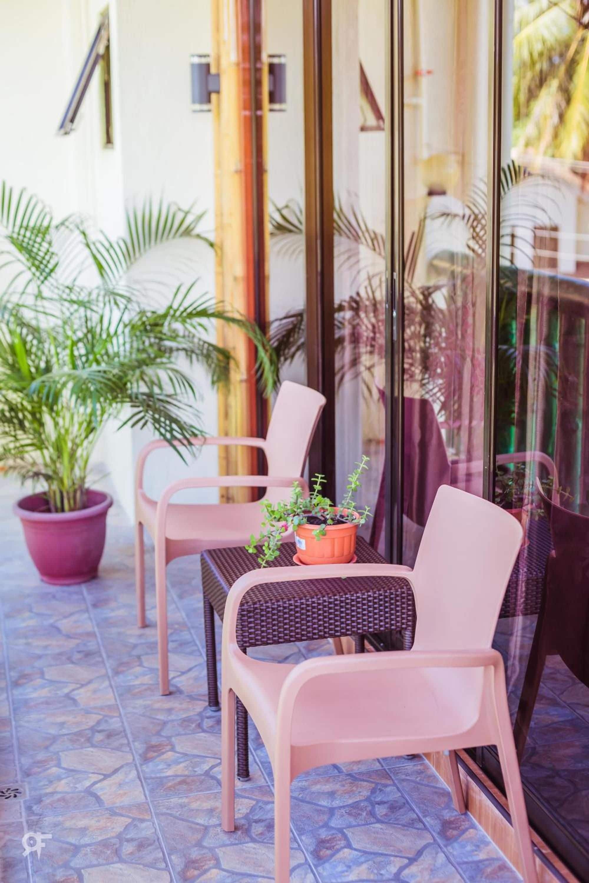 An outdoor seating area with two chairs and a table, surrounded by potted plants.