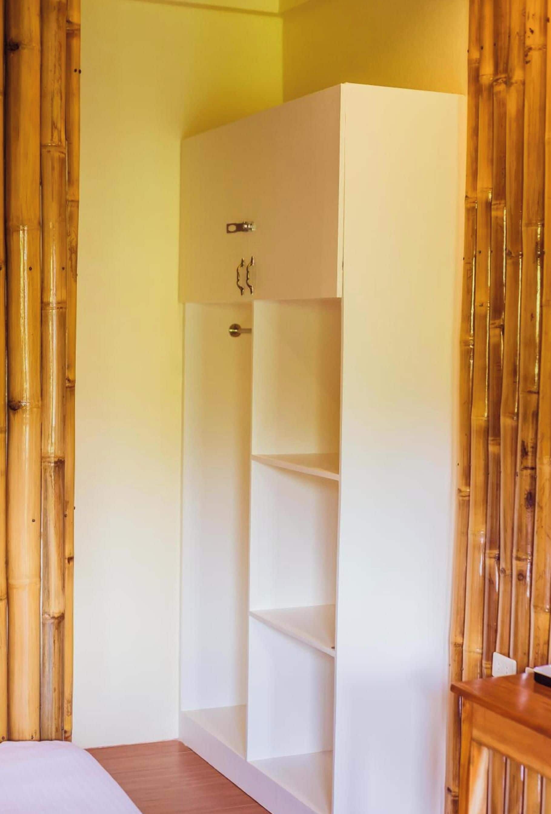 A room with a white wardrobe, a bed, and a wooden floor.