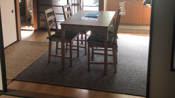 A traditional Japanese-style room with tatami flooring, a wooden table with cushions, and a sliding door leading to a kitchen area. - Kanazawa-Hachitabi Sennichi (Kanazawa)