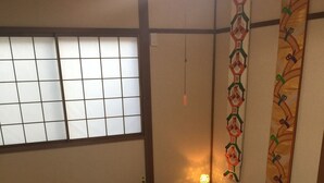 A traditional Japanese-style room with tatami flooring, a shoji screen, and a hanging decorative piece. - Kanazawa-Hachitabi Sennichi (Kanazawa)