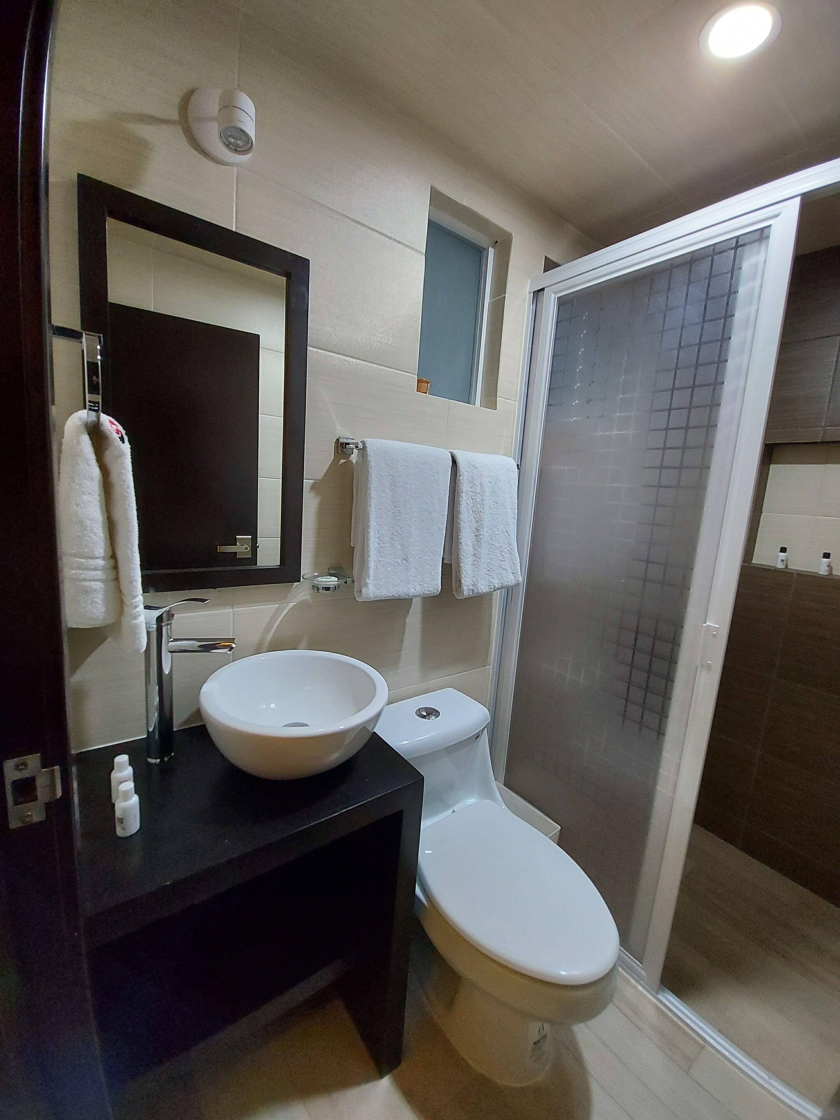 A modern bathroom with a black vanity, white sink, and a glass shower enclosure.