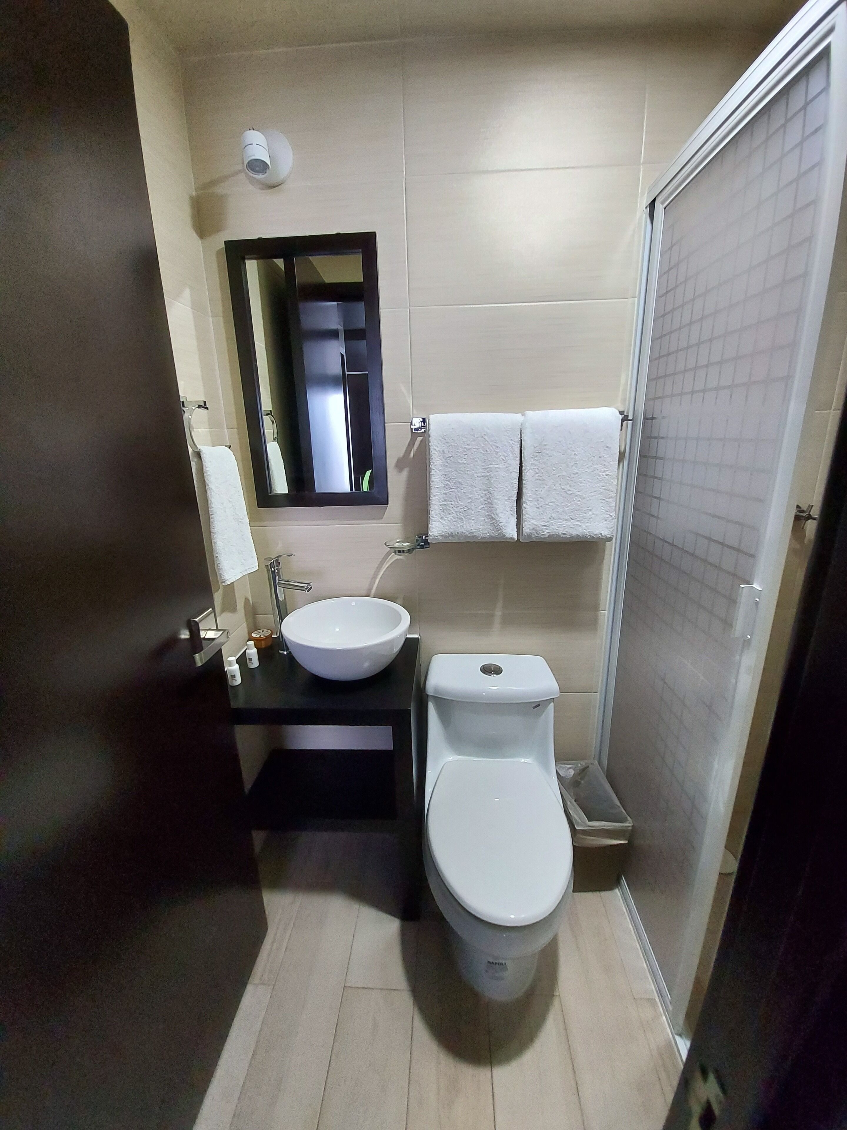 A compact bathroom with a sink, toilet, and a mirror.