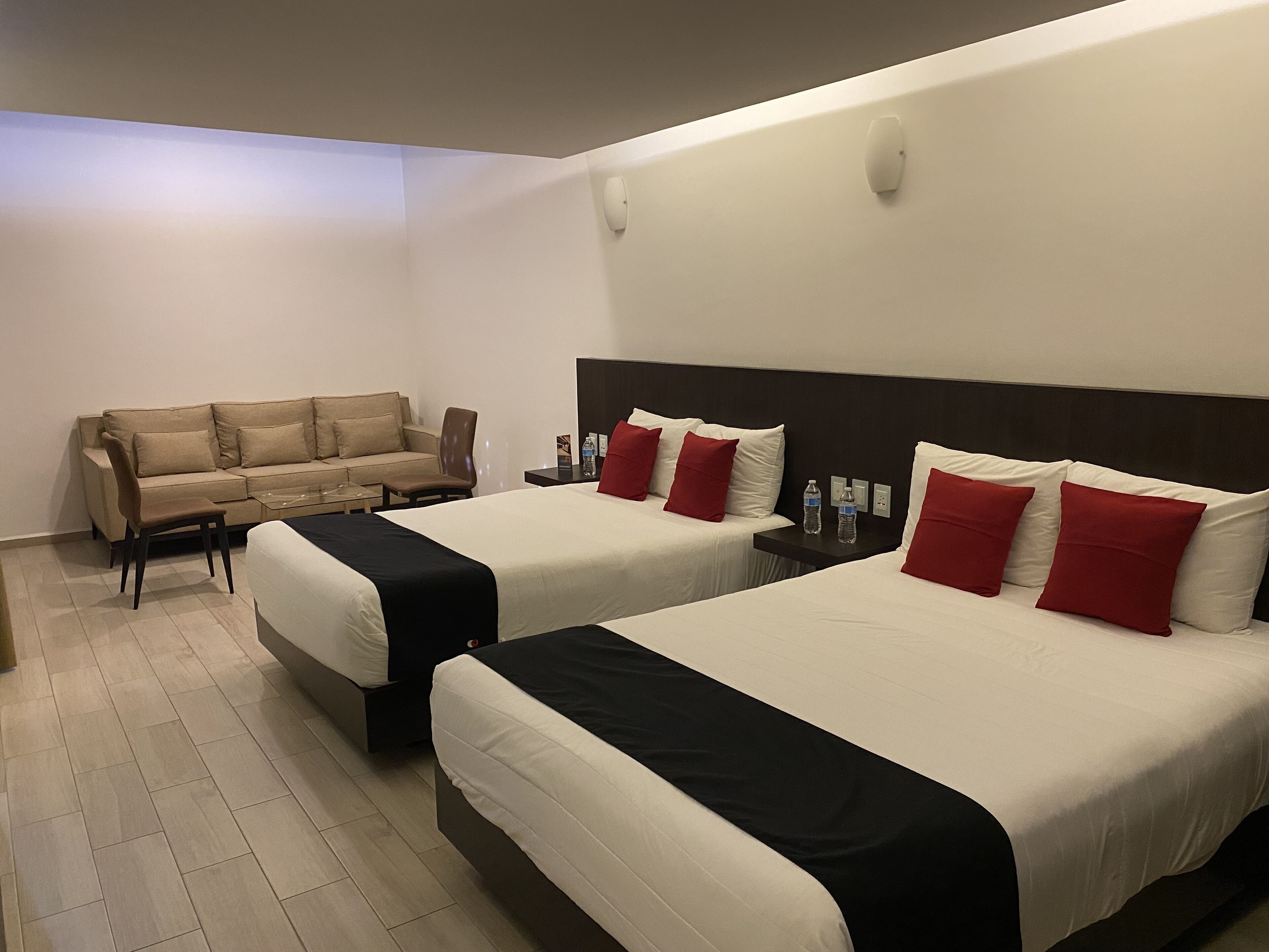 A hotel room with two beds, a sofa, and a coffee table.