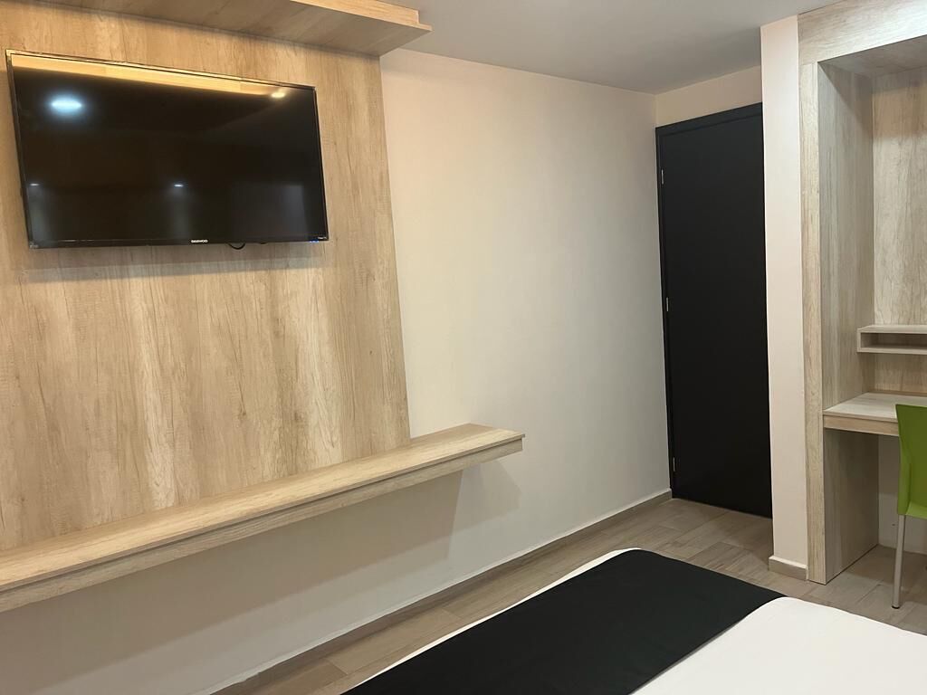 A modern room with a mounted TV, a wooden accent wall, a black mat on the floor, and a door in the background.