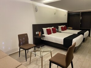 Een hotelkamer met twee bedden, een stoel, een klein tafeltje en een garderobe.