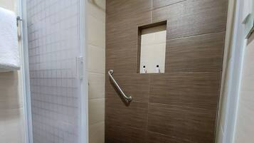A bathroom with a shower, a toilet, and a small mirror.