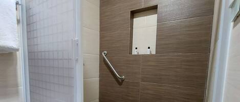 A bathroom with a shower, a toilet, and a small mirror.