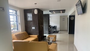 Un salon moderne avec un canapé beige, une table basse et un coin repas comprenant des chaises et une table.