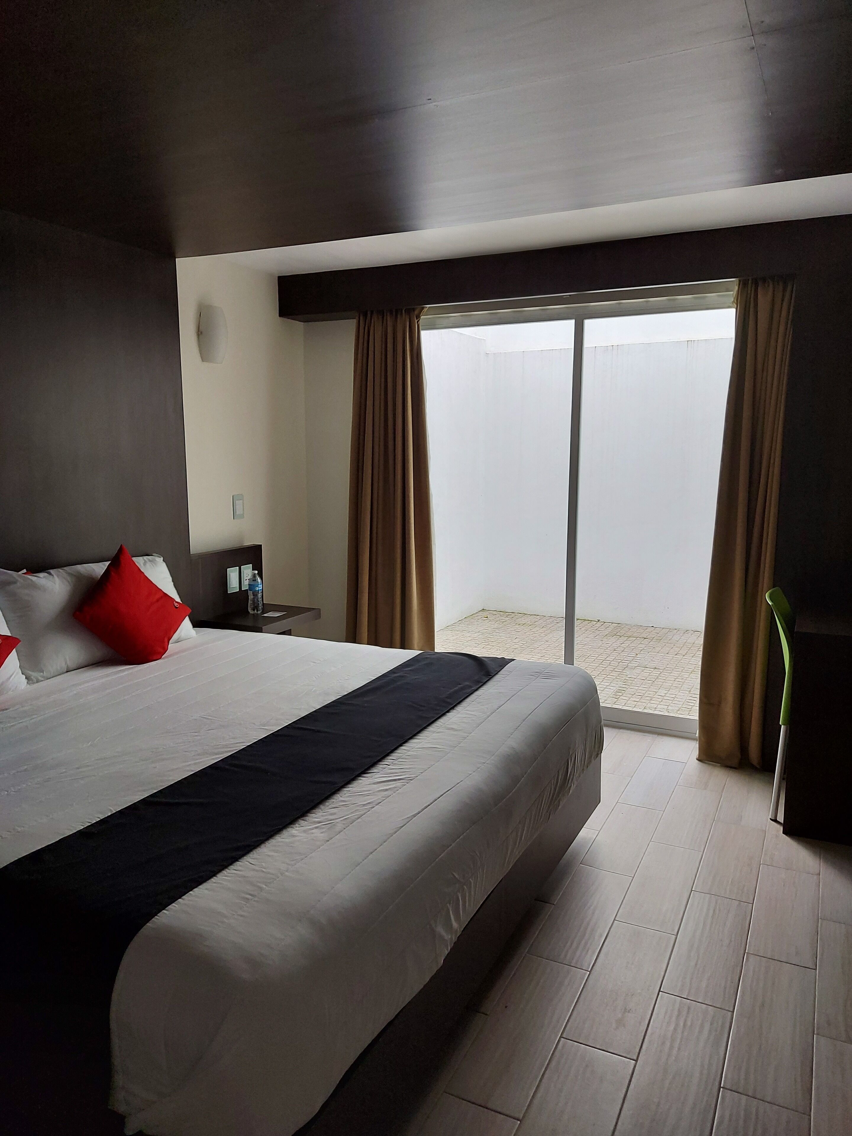 Een hotelkamer met een groot bed, een nachtkastje, een lamp en uitzicht op het strand door het raam.