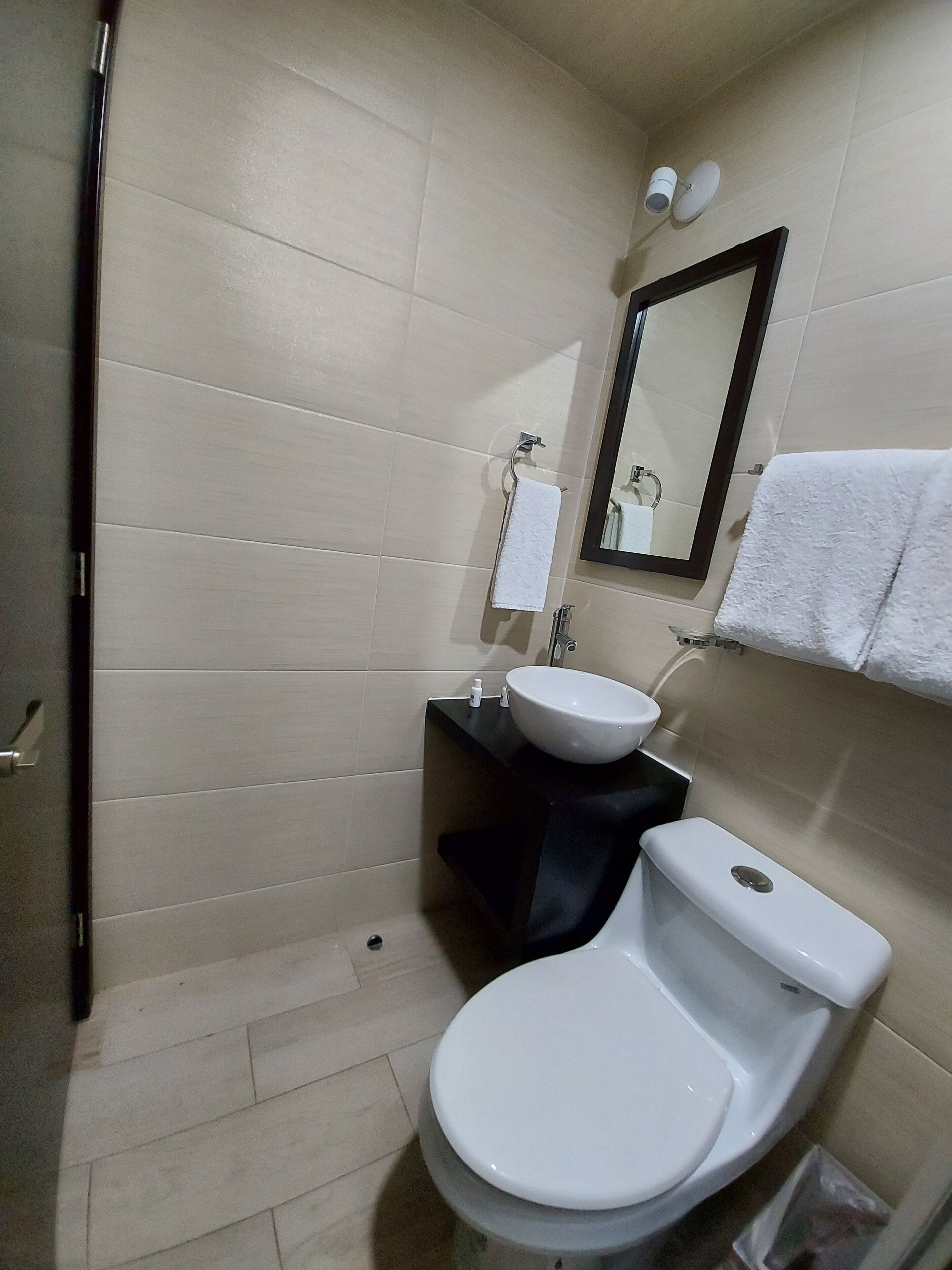 Un baño pequeño con inodoro, lavamanos y espejo.