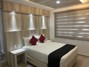 Een moderne slaapkamer met een houten hoofdbord, een nachtkastje en een raam met zonwering.