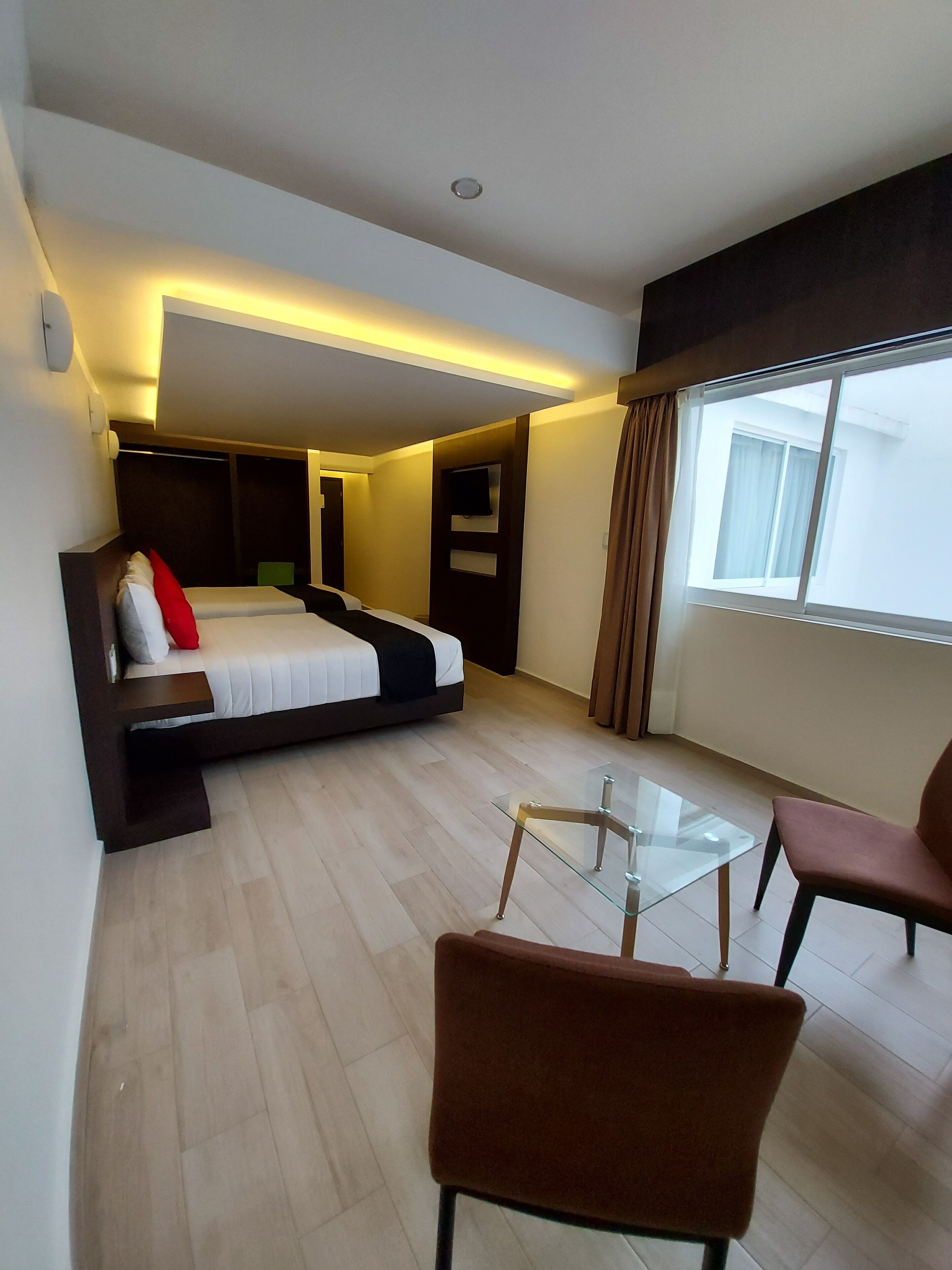 Una habitación de hotel moderna con una cama, una mesa de vidrio y una silla.